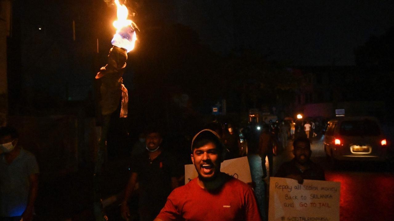 Protestors hold placards and torches during a demonstration against the surge in prices and shortage of fuel and other essential commodities in Colombo. Pic/PTI